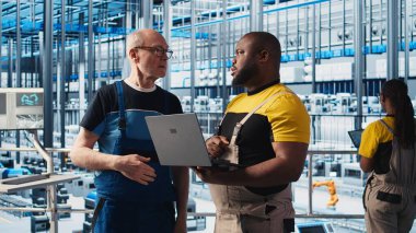 Akıllı fabrika kıdemli mühendisi yeni stajyere robotik silah kullanmayı öğretiyor. Endüstri 4.0 Endüstriyel Santral Takım Lideri ve stajyer otomatik makineleri kontrol ederek, iş akışının devamlılığını sağlıyor, kamera A