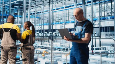 4.0 endüstriyel fabrika kıdemli mühendisi dizüstü bilgisayar yazılımı kullanarak robot makineleri otomatikleştiriyor. Deneyimli teknisyen akıllı fabrikada yapay zeka özelliklerini not defteri, kamera A kullanarak uyguluyor.