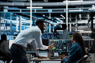 Data center admins programming infrastructure used for machine learning training. Server hub IT professionals collaborating running code on PC to upgrade artificial intelligence systems