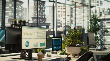 Parlak ofis ortamında analitik veri belgeleriyle dolu modern çalışma alanı ve saksı bitkileri. Ekranda gösterilen dijital istatistik çizelgeleriyle birlikte masadaki tablet, dönüm noktası