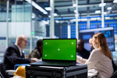 Yatırımcılar kroma anahtar defterindeki ölçülere bakıp fabrikanın genişleme ihtimallerini araştırıyorlar. Üretim fabrikası yöneticileri, yeşil ekran dizüstü bilgisayarındaki üretim verilerini analiz etmek üzere hissedarlarla bir araya geliyor.