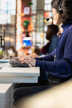 Mutsuz müşterilerle ilgilenen bir merkez ajanını ara. Ofis masasındaki kulaklıkla konuş. Müşterilerle ilgilenen müşteri desteği temsilcisi şirket çalışma alanında şikayette bulundu