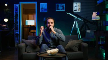 TV ekranına patlamış mısır fırlatan, TV 'de canlı yayında futbol maçı izleyen, karşı takımın attığı gollere öfkeyle tepki veren bir adam. Evdeki spor taraftarı hakemlik hatasından rahatsız oldu, kamera B