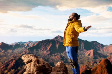 Dağın tepesinde meditasyon yapan maceraperest, tepeye başarıyla tırmanıyor ve manzaranın tadını çıkarıyor. Genç sakin zen yolcusu yürüyüş ve meditasyon yapıyor..
