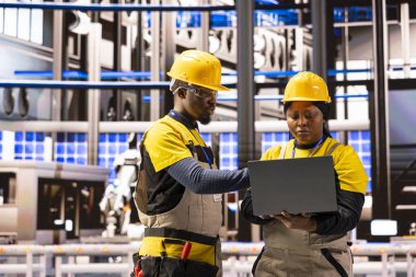 Profesyonel mühendisler fabrika otomasyon sistemini analiz ediyor ve kusursuz üretim ve geliştirilmiş üretim için robotik kol performansını optimize ediyorlar. Endüstriyel enerji santralinde takım çalışması ve yenilik.