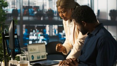 Ofisteki çalışanlar dizüstü bilgisayardan yöneticiye gelir rakamlarını gösteriyor. İşi bitirdikten sonra şirket istatistiksel numaralarını yöneticiye sunan muhasebeci, kamera A