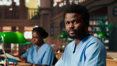 Afro-amerikan tıp öğrencisi tıp fakültesi kütüphanesinde farmakoloji öğreniyor. Tıp fakültesi, sağlık kariyeri için akademik eğitim. Kamera B.