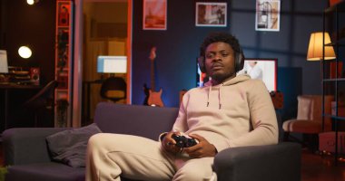 Evde oturan oyuncu boş zamanlarında dizüstü bilgisayarında oyunların keyfini çıkarıyor. Oturma odasında kanepede oturan siyah adam, bilgisayar oyunu oynuyor, işten sonra dinleniyor. Kamera B.