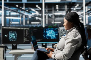 Gülümseyen sunucu merkezi çalışanı altyapı arızasını azaltmak için veri analiz grafiğine bakıyor. Jolly Veri Merkezi Sistem Yöneticisi Yapay Zeka görselleştirme gösterge paneline bakarak ekipman arızalarını belirler