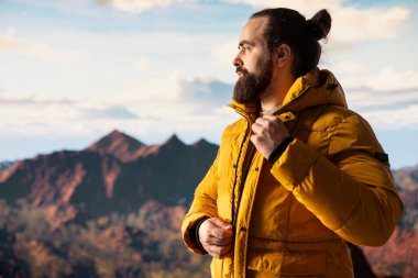 Bir dağ zirvesinde tek başına duran gezgin, sersemletici tepe manzarası, bulutlar ve sonsuz gökyüzü, maceraperest. Nefes kesen manzara kararlılığı ve hırsı simgeler..