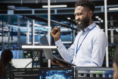 Bilgi işleme makine öğrenme sistemlerini kurduktan sonra kutlama yapan mutlu veri merkezi yönetimi. Neşeli bilişim uzmanı, sunucu tarım işlemlerini geliştirmek için sinirsel ağları eğittikten sonra memnun oldu