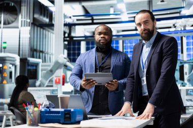 Çok ırklı güneş paneli mühendisliği ekibi, temiz yenilenebilir enerji üretimi üzerinde çalışarak fabrikada veri bilgilerini paylaşıyor. Yenilik ve takım çalışması ile sürdürülebilir gücü desteklemek.