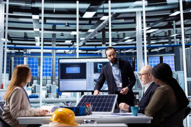 Müdür, endüstriyel tesislerdeki fabrika yöneticilerine güneş paneli teknolojisi ve otomatikleştirilmiş üretim kavramlarını sunarak, yatırım ve genişleme stratejisini göstermek için dijital diyagramlardan yararlanıyor