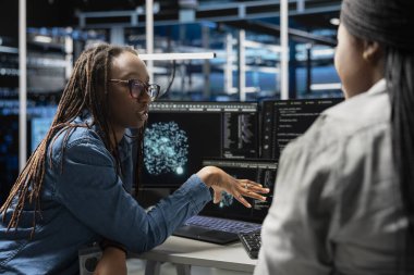 Veri merkezi ekip lideri, hataları tespit etmek için yapay zeka görselleştirme araçları kullanan mühendisi denetliyor. Sunucu merkezi yöneticisi donanım hatalarını tespit etmek için yapay zeka geliştirilmiş içgörüleri kullanarak çalışanı denetler