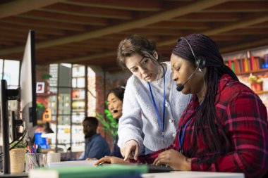 Çağrı merkezi müdürü yeni elemana rehberlik ediyor, soruları cevaplıyor. Müşteri desteği, yeni çalışanlar için oryantasyon oturumları düzenleyen yatılı uzman.