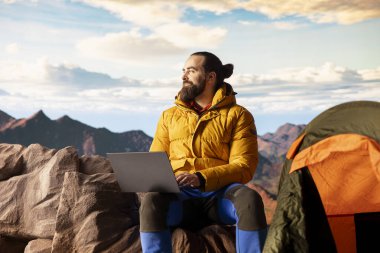 İşkolik kâşif her zaman kesintisiz işlere bağlanır ve bağımlıdır. Dağın tepesinde dizüstü bilgisayarını açar. İnternet bağımlılığına sahip genç gezgin güçlü bir sinyalin keyfini çıkarıyor.