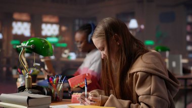 Afrika kökenli Amerikalı dişçi, insan dişlerinin plastik modelini inceliyor, kampüs kütüphanesinde stomatoloji çalışmaları yapıyor. Erkek öğrenci dişçiliği ya da oral sağlığı öğrenir. Kamera A.