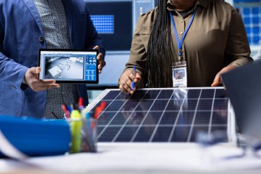 Fotovoltaik fabrikası müdürüyle buluşan yatırımcılar, tablet kullanarak güneş pili tasarımlarını gözden geçirecekler. Güneş panelleri teknik özellikleri analiz eden iş adamları yerleştirir. Cihazı kullanır, kapatır.