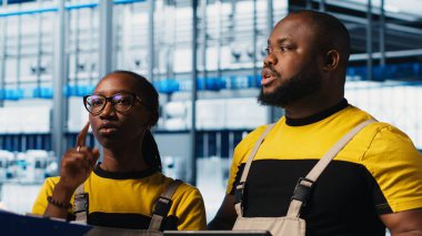 Akıllı fabrika lideri tesisin zeminindeki robotik silah operasyonunu denetleyen çalışanlarla konuşuyor. Endüstri 4.0 fabrika işçileri, sorun çıkarılan hatalar hakkında beyin fırtınası yapıyorlar, kamera A