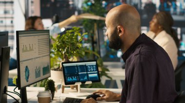 İşyerinde muhasebe, iş arkadaşlarıyla konuşurken aynı zamanda bilgisayar üzerinden finansal veriler giriyor. Modern ofiste çalışan çalışanlar, verileri ve kamera A 'yı karşılaştırırken iş arkadaşlarıyla sohbet ediyorlar.