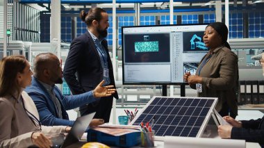 Fotovoltaik fabrika müdürleri güneş teknolojisi raporlarını inceliyor. Hissedarlar, yeşil enerji üretiminde gelecek yatırım fırsatlarını tartışan A kamerasını okuyorlar.