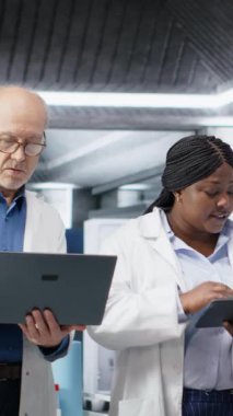 Biolab 'daki üç bilim adamının dikey video portresi biyokimya ve moleküler bilimle tanıları yansıtan bir araştırma çalışması yürütüyor. Tıp için sağlık hizmetleri yeniliği. Kamera B.