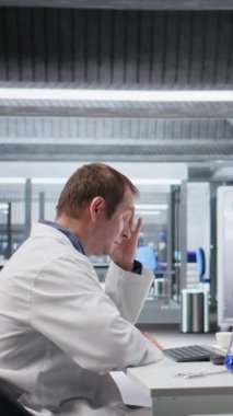 Dikey video tatminsiz bilim adamı laboratuvarda karmaşık deney verilerini çözmeye çalışıyor. Biyoteknoloji ve genetik araştırmaları ile uğraşan kafası karışmış ve başarısız bir adam.