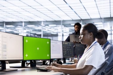 Sunucu odası teknisyeni, yeşil ekran bilgisayarı kullanarak güvenlik duvarı yanlış yapılandırmalarını buluyor. Kadın, krom anahtar PC kullanarak veri aktarım oranlarının yavaşlamasına yol açan sistem darboğazlarını kontrol ediyor