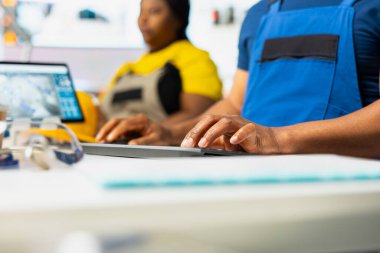 Afrikalı Amerikalı işçiler endüstriyel parametreleri güneş enerjisi üretimi için ayarlıyorlar, yüksek teknoloji üretim tesisinde çalışıyorlar. Bilgisayar kurulumunda teknik verileri analiz eden teknisyen. Kapat..