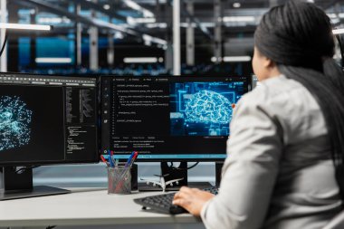 Makine öğrenimi için kullanılan sinirsel ağ veri merkezini denetleyen sistem yöneticisi. Sunucu çiftliğinde çalışan bir kadın yapay zeka yükünü optimize etmek için çalışıyor.