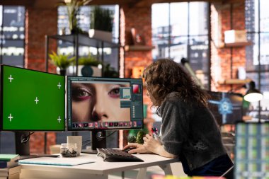 Serbest tasarımcı, ajans ofisindeki krom anahtar ekranın yanında gelişmiş tasarım yazılımı kullanarak fotoğraf düzenleme üzerinde çalışıyor. Çalışma alanı çevrimiçi çalışmalar için yaratıcılığı ve yeniliği teşvik eder.