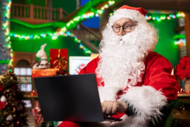 Noel Baba dünya çapındaki oyuncak sevkiyatlarını izlemek için dizüstü bilgisayardaki haritaları kullanıyor. Noel Baba yüzgeç festivali atölyesi küresel hediye dağıtımlarını takip ediyor.