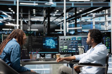 Belden aşağısı felçli ve iş arkadaşı olan bir mühendis yapay zeka ve makine eğitimi için gerekli veri merkezi ekipmanlarını kuruyor. Özürlü sunucu ve iş arkadaşı yapay zeka araçları kullanıyor.