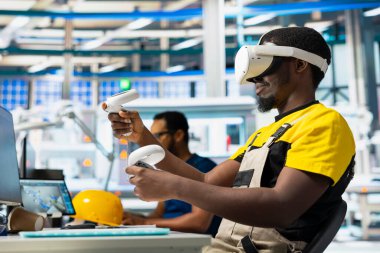 Siyah endüstriyel fabrika çalışanı sistem performansını denetlemek için sanal gerçeklik teçhizatı kullanıyor. Güneş panelleri imalat fabrikası teknisyeni enerji üretimini izlemek için VR gözlükleri kullanıyor.