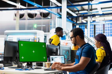 Siyah mühendis, güneş paneli imalat tesisinde kroma anahtar ekranı vasıtasıyla robotik kol ayarlarını ayarlıyor, makine performans sorunlarını teşhis ediyor. Fotovoltaik fabrikası teknisyeni..