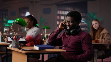 Kaba adam kütüphanedeki bir telefona cevap veriyor ve insanları rahatsız ediyor, çok gürültü yapıyor. Öğrenciler sessiz kalmak istiyor. Öğrenirken ve okurken odaklanamıyorlar. Kamera A.