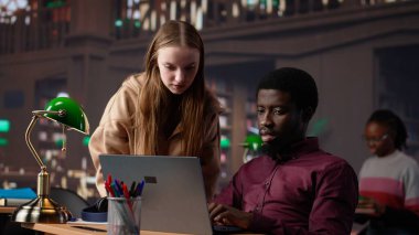 Kampüs kütüphanesinde takım çalışması yapan çok ırklı öğrenciler akademik veritabanına ve çeşitli kitaplarla araştırma koleksiyonuna danışıyorlar. Genç yetişkinler yüksek notları garanti eder. Kamera A.
