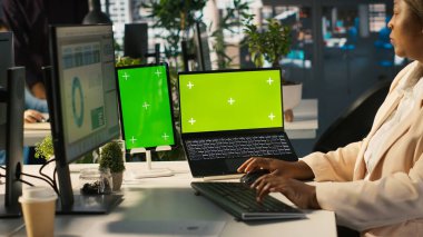 Ofis masasında bilgisayardaki belgeleri düzenleyen çalışanın yanında izole ekran bilgisayarı ve tablet var. Veri tablolarını analiz eden, istatistiksel bilgileri yorumlayan, kamera A 'nın yanındaki krom anahtar aygıtlar