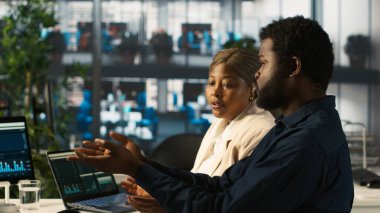 Yönetici, çalışanlarıyla gelir, karlılık ve operasyonel verimlilik için kilit performans göstergeleri hakkında konuşuyor. Afrika kökenli Amerikalı yönetici, iş yerindeki çalışanı denetliyor, kamera A.