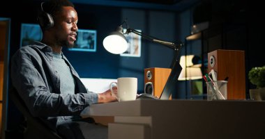 Genç, ofisinden online bir toplantıya katılıp ortaklarıyla uzaktan tartışıyor. Gülümseyen siyah adam sanal iletişimle, uzaktan teknolojiyle meşgul oluyor. Kamera A.