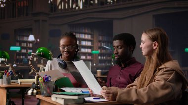 Üniversite öğrencileri kampüs kütüphanesinde uluslararası işletme yönetimi ve yönetimine odaklanarak başlangıç projesinde işbirliği yapıyorlar. Akademik diplomaları için çok çalışıyorlar. Kamera B.