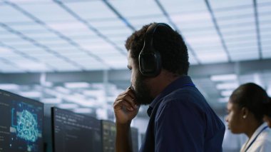 Bilgisayar bilimci sunucu odasında kulaklık takıyor, en az dinlenme süresini sağlamak için çalışıyor. Veri merkezinde podcast dinlemek için ses aygıtı kullanan mühendis, performansı gözlemliyor, kamera A