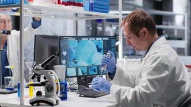 Bilimadamı, laboratuvar deneyleri sırasında örnek damlasını kavanoza aktarmak için pipette kullanır. Biyoteknoloji araştırmalarını, moleküler biyolojiyi ve yenilikleri vurgulayan hassas bir prosedür. Kamera B.