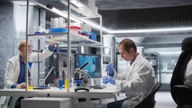 Bilimadamı, laboratuvar deneyleri sırasında örnek damlasını kavanoza aktarmak için pipette kullanır. Biyoteknoloji araştırmalarını, moleküler biyolojiyi ve yenilikleri vurgulayan hassas bir prosedür. Kamera A.