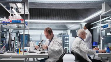 Erkek bilim uzmanı, biyoloji bilimi için mikroskop altında örnekler gözlemler, genetik araştırma ve biyomühendisliği destekler. Farmasötik yenilik için laboratuvar testleri. Kamera A.