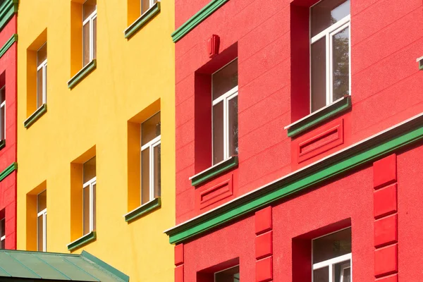 brightly colored building in burgundy and yellow with green cornice