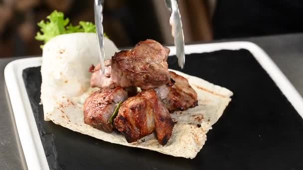 Кухар відкладає смажене м'ясо на тарілці — стокове відео