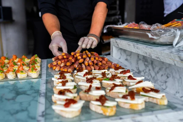 Manos en guantes con comida en la mesa del banquete — Foto de Stock