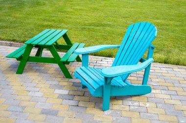 Tahta sandalye ve çimlerin yanında bir masa.