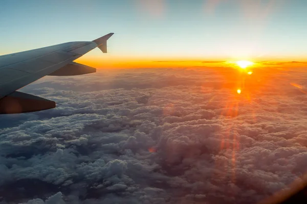 sunset from the window above the clouds with airplane wing